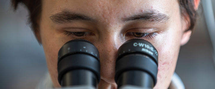 Closeup of person looking into microscop