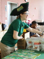 Image of Kerry Hentges wearing a black pirate-like hat and in Mason attire, handing food out.