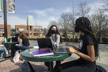 Students sit outside at a table at the Fairfax Campus